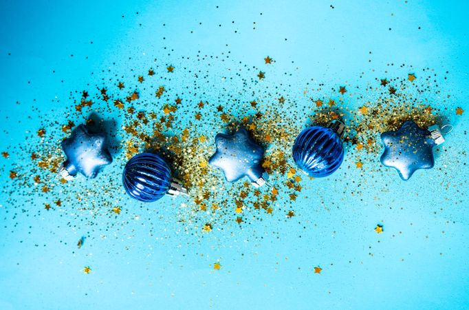 Festive xmas card concept of star glitter and baubles on blue background