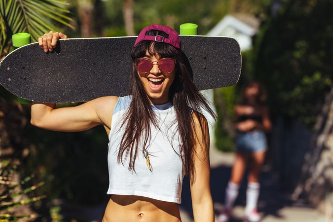 Excited woman holding a skateboard on a summer day