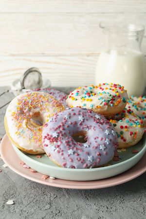 Concept of tasty food with donuts and milk on gray background