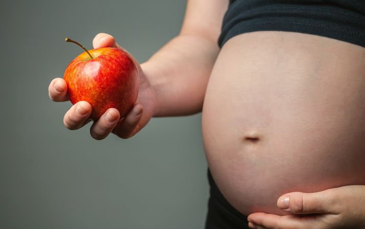 Pregnant woman holding an apple