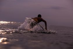 Man on surf board floating on water and cloudy sky