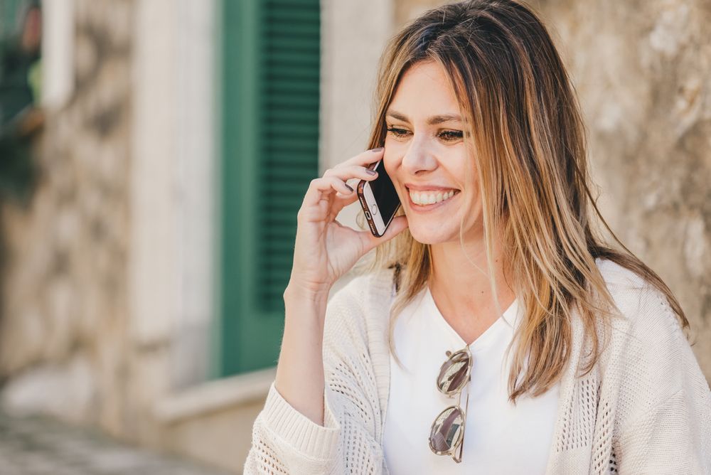 Woman with smartphone sitting on stone steps of stairs