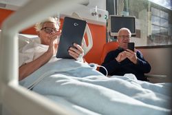 Concentrated older couple browsing gadgets in clinic