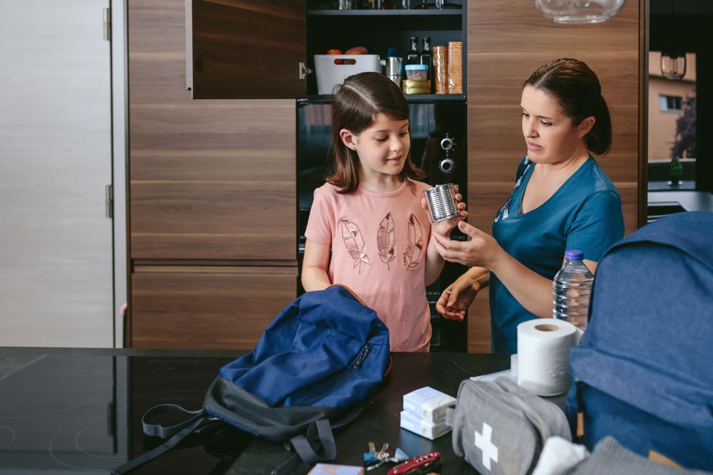 Mother preparing emergency backpack with her daughter