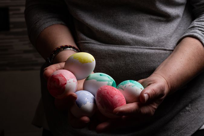 Woman holding many Easter eggs in darkness