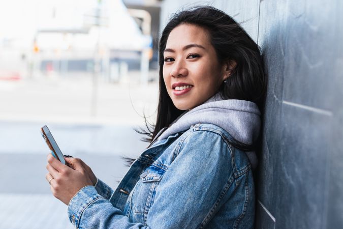 Long hair brunette Asian woman using mobile phone in the street