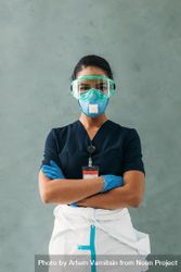 Portrait of Black female doctor with arms crossed in PPE gear, vertical bDLGVb