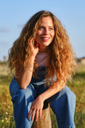 Smiling woman sitting on tree trunk in countryside