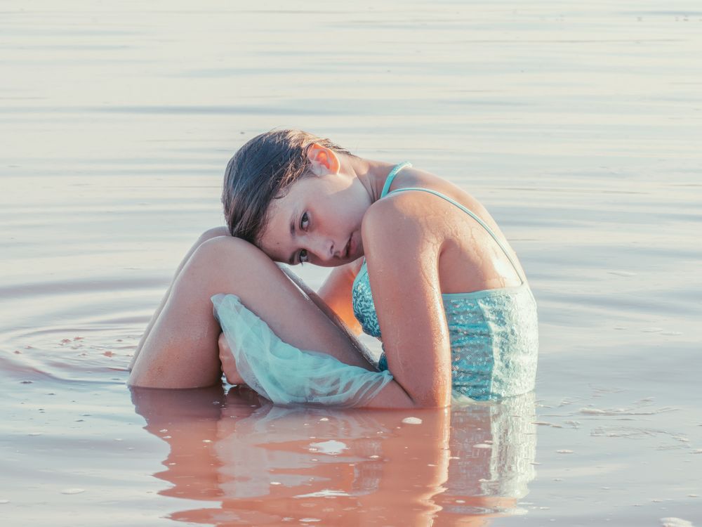 Teenage girl sitting in fresh water in sunny day