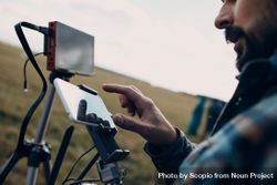 Side view of man using two smartphones attached to screen stand outdoor 0JJMZ0