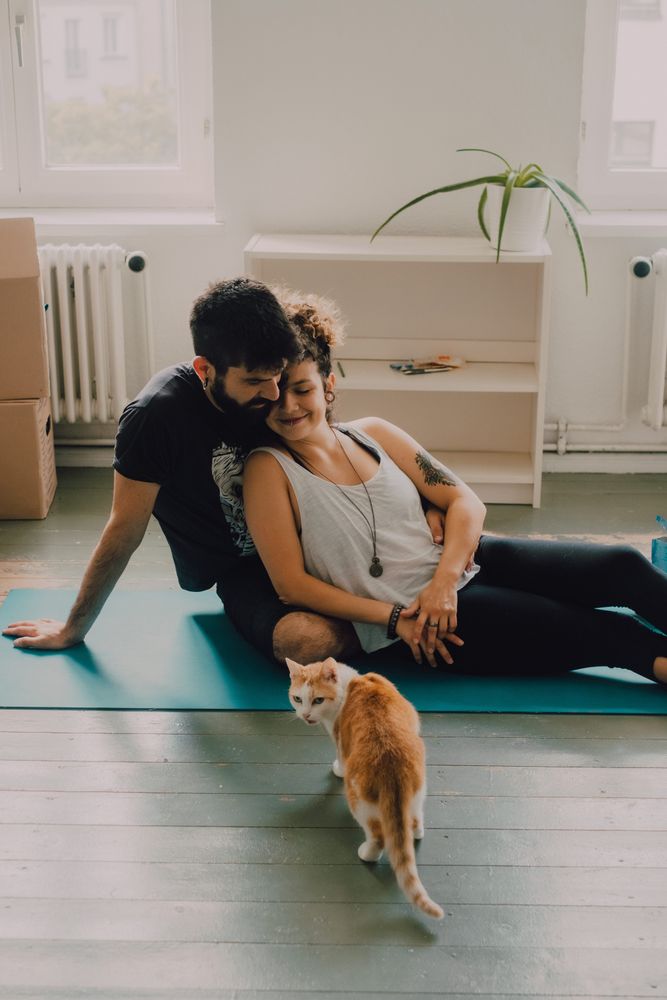 Loving couple cuddling on floor while cat walking around
