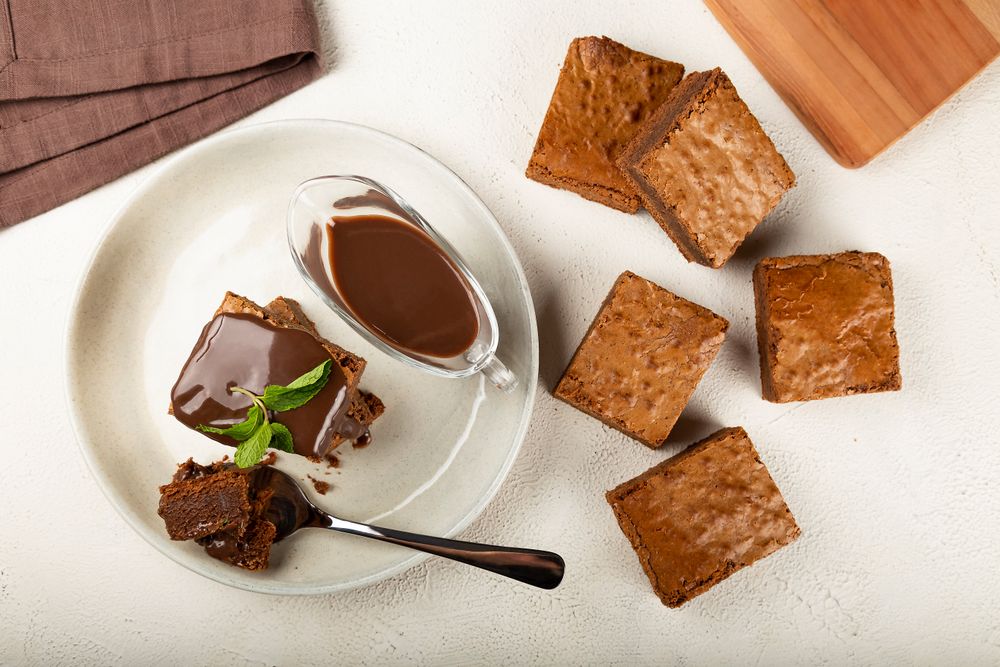 Top view of brownies and spoon served with sauce and mint garnish