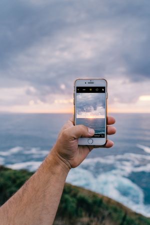 Person taking photo of cliffs and sea
