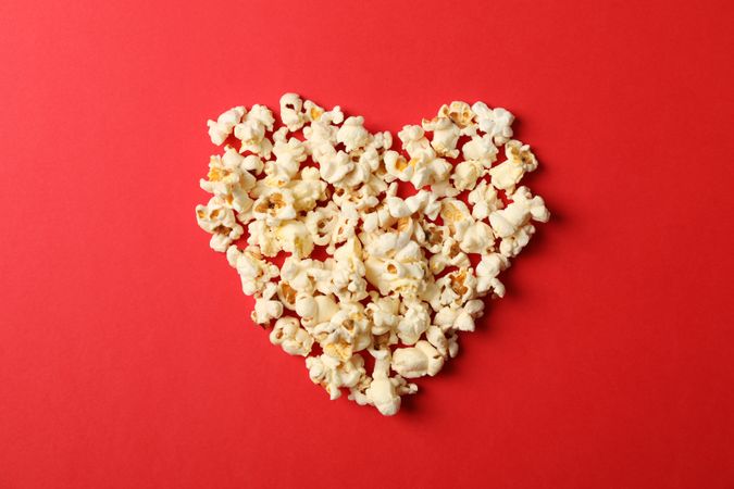 Flat lay composition with popcorn heart on red background, space for text