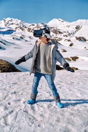 Boy playing VR game near snowy hills