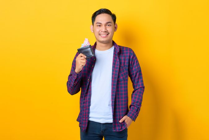 Smiling man holding wallet with cash