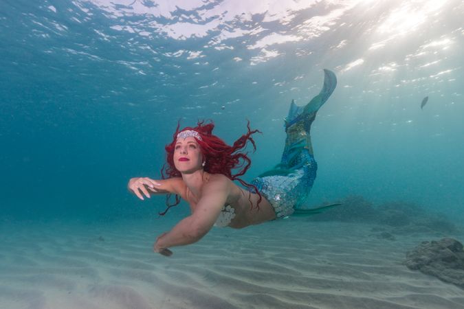 Redhead fairytale female mermaid swimming underwater