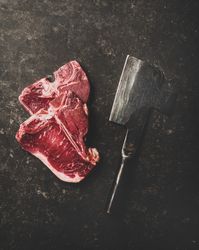 Two T-bone steaks with cleaver on butchers block