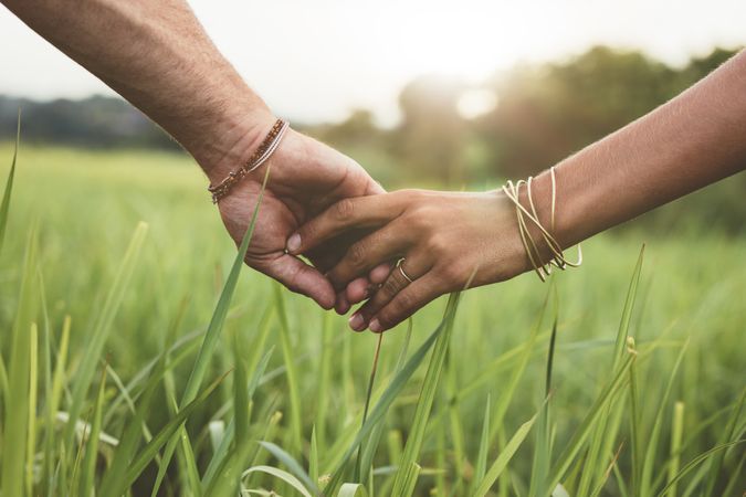 Shot of romantic couple holding hands in a field