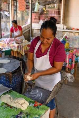 Woman preparing corn tortillas on street