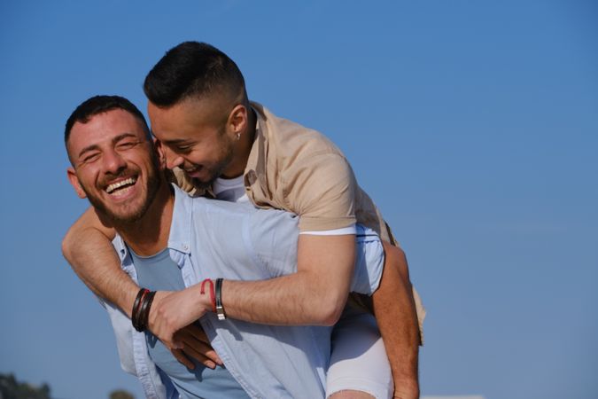 Happy gay couple playing piggyback