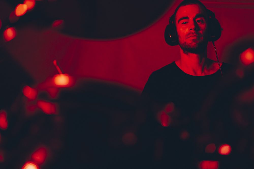 Man with drumsticks playing on drums in redness