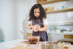 Little girl in cooking apron baking in the kitchen