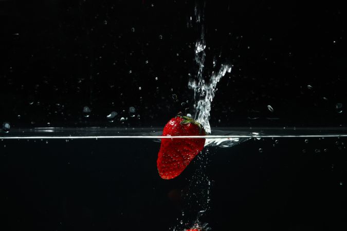 Side view of clear water on dark background with strawberry