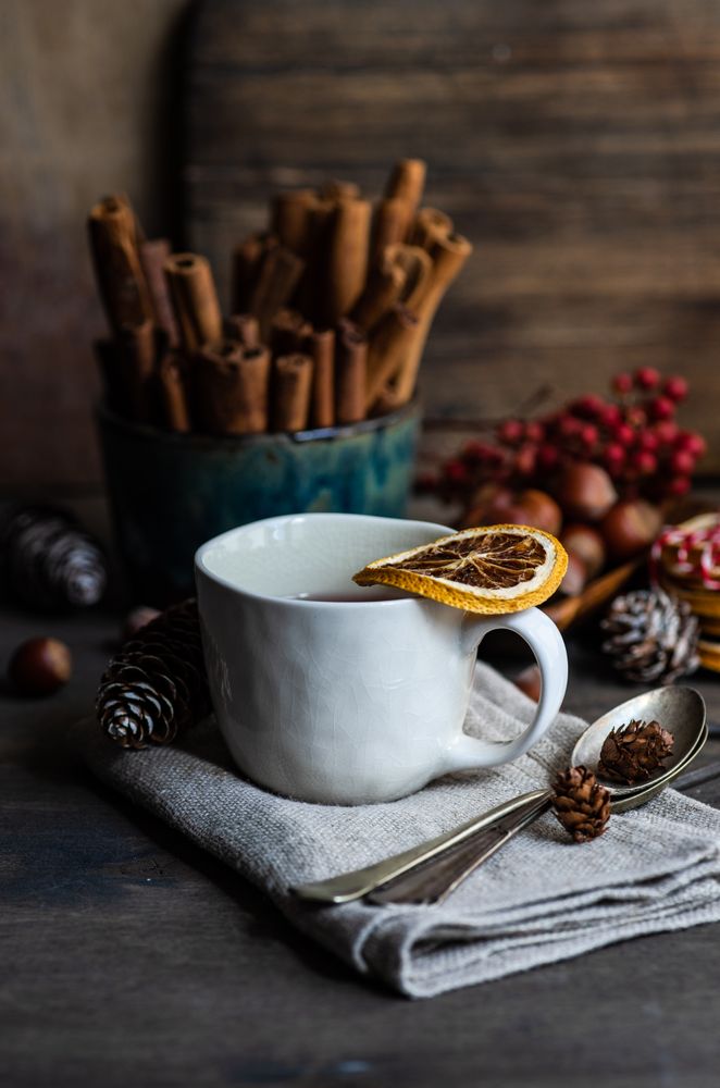 Dried orange slices balanced on mugs of Christmassy hot tea