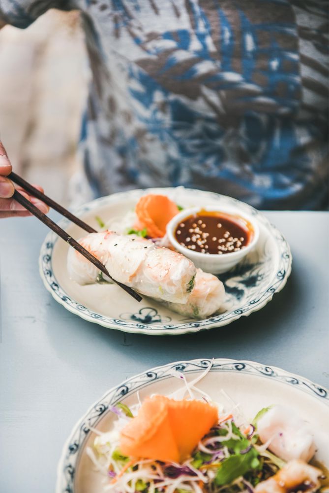 Man holding spring roll between chop sticks