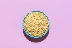 Spaghetti with cheese and black pepper, top view on a purple background