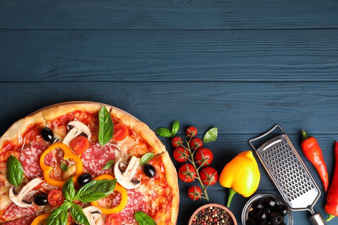 Delicious pizza and ingredients on wooden background, copy space