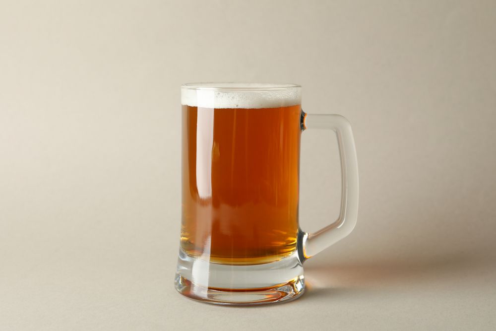 Glass of beer on gray background, space for text