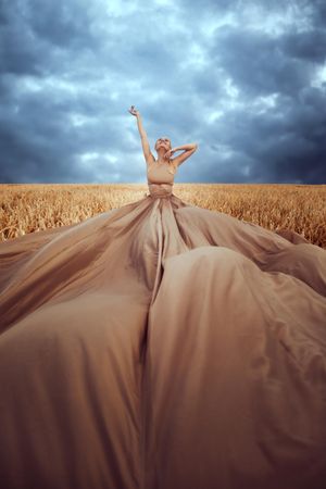 Woman in flying beige dress in wheat field