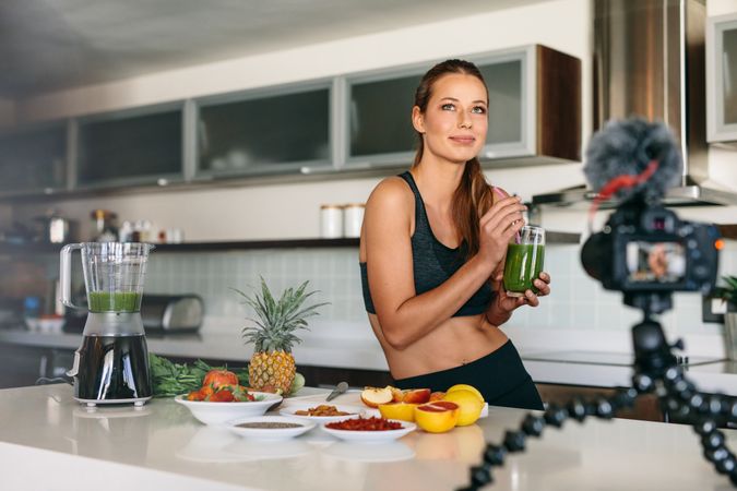 Fit blogger enjoying healthy juice in front of digital camera