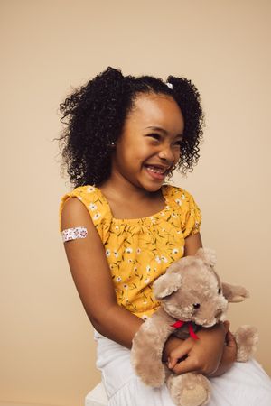 Cute girl with bandage on arm after getting a vaccine smiling