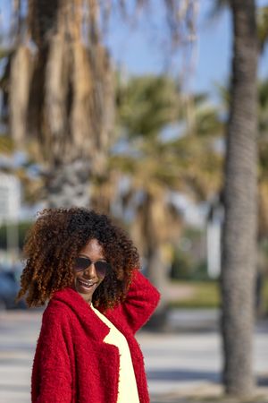 Happy female with hand to her hair on street with palm trees