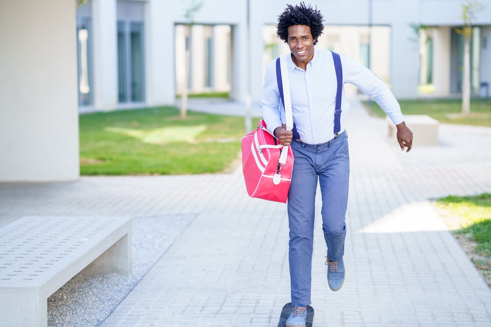 Smiling man with sports bag roller skating out of office