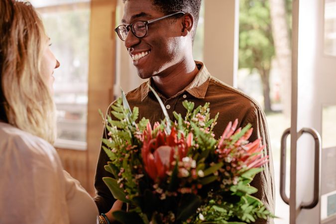 Happy young man giving young woman flowers on a date