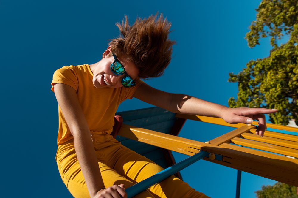 Cool stylish young woman in vibrant clothes on playground