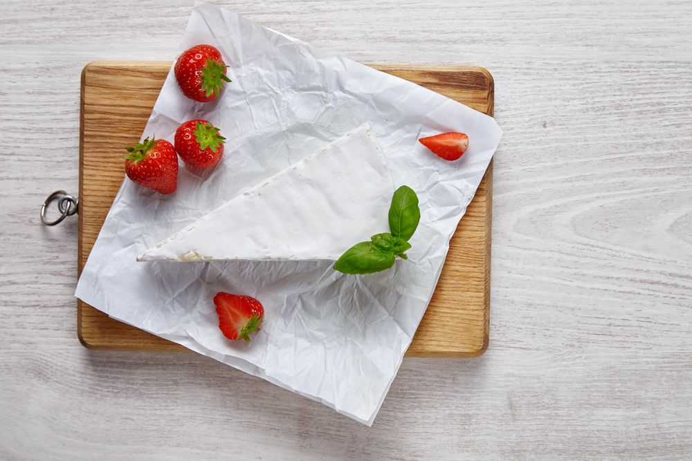 Above view of slice of cheese with strawberries