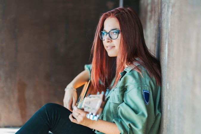 Romantic woman playing guitar leaning on wall