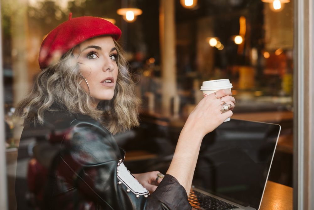 Dreamy woman using laptop in cafe