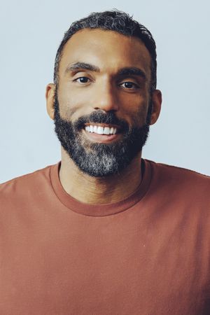 Head shot of happy Black male in grey studio