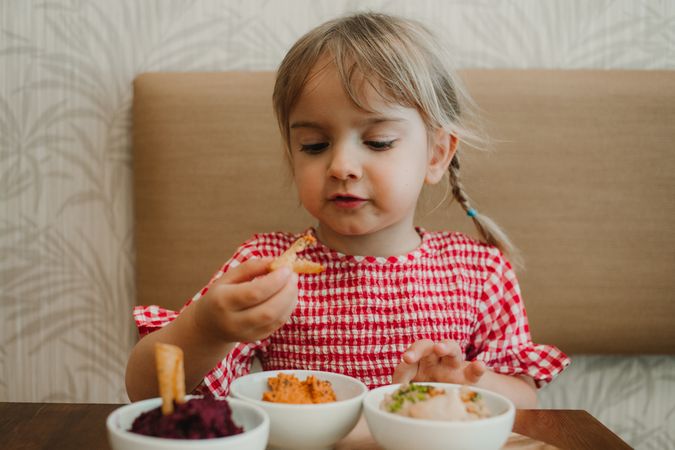 Girl eating with hand assorted food at table