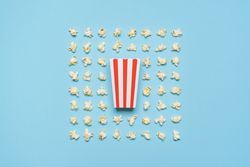 Popcorn flakes and striped box flat lay on a blue background