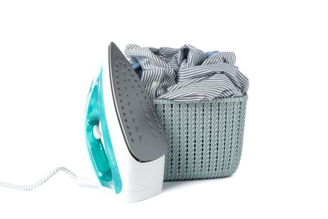 Iron and basket with clothes isolated on blank background