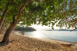 Female swinging on tranquil sandy beach