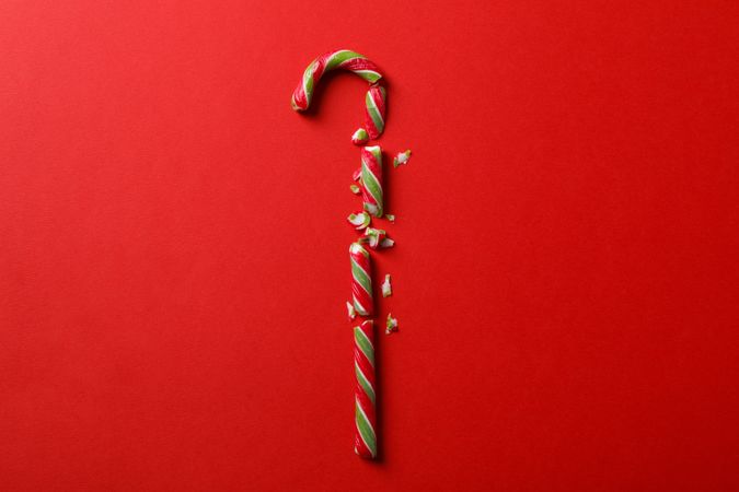 Broken candy cane on red background, space for text