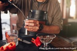 Closeup of bartender hands pouring alcoholic drink into a jigger 5qP3a0